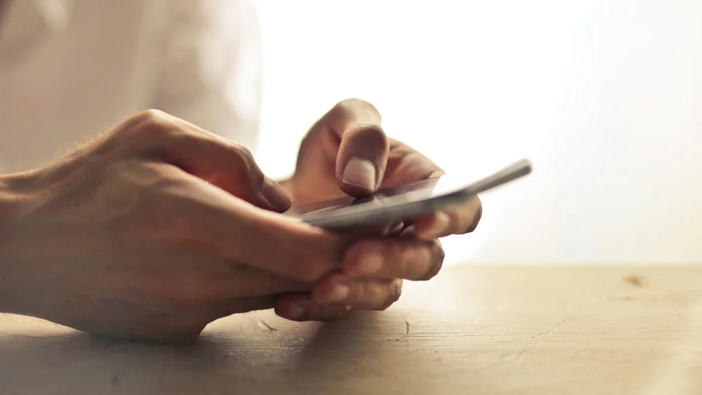 Hands holding an Iphone as Philippine announce 24/7 helpline to aid responsible gaming measures