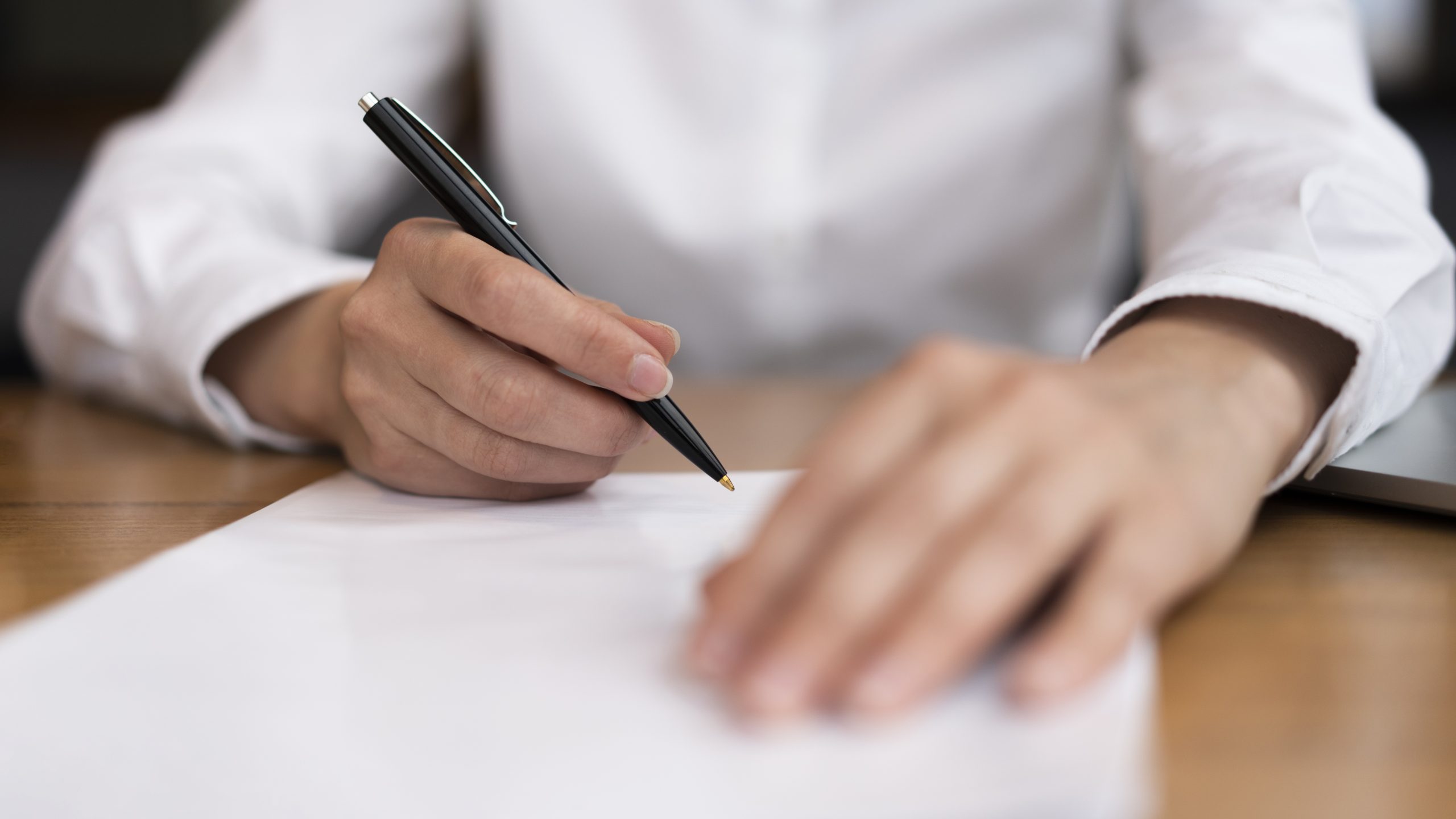 Hands signing paperwork signalling SJM's acquisition of L'Arc